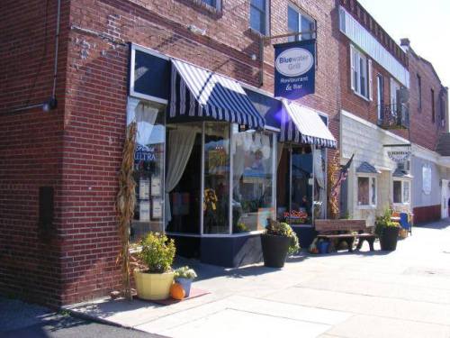 A brick building with striped awnings, featuring a restaurant entrance and seasonal decorations outside.