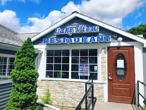 Exterior of Lake View Restaurant with a blue sign, open window, and stone accents under a partly cloudy sky.