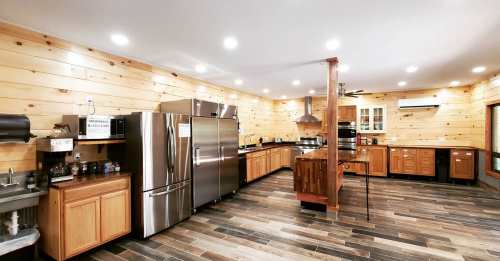 Modern kitchen with wooden walls, stainless steel appliances, and ample counter space, featuring warm lighting.