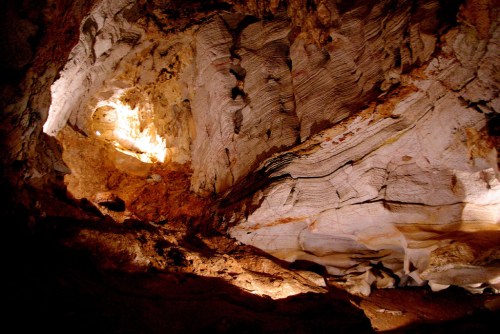 A dimly lit cave interior showcasing textured rock formations and illuminated areas.