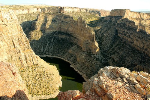A panoramic view of a deep canyon with steep rock walls surrounding a winding river below.