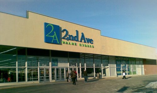 Exterior of a 2nd Ave Value Stores building with large signage and shoppers entering. Clear blue sky above.