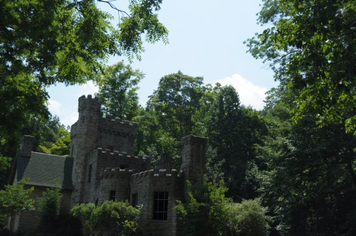 A stone castle surrounded by lush green trees under a clear blue sky.