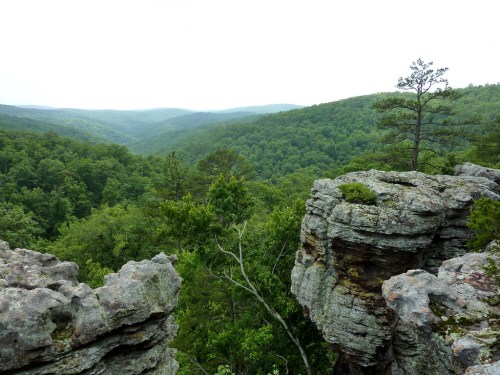 A scenic view of lush green mountains and rocky cliffs under a cloudy sky.