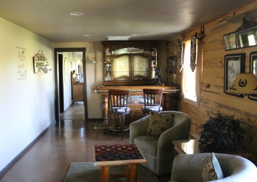Cozy interior featuring a wooden bar, comfortable seating, and rustic decor in a warmly lit room.