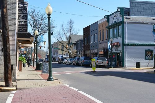 A quiet street scene with shops, parked cars, and clear blue skies in a small town.