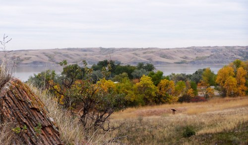 A serene landscape featuring rolling hills, a river, and autumn foliage in shades of yellow and green.