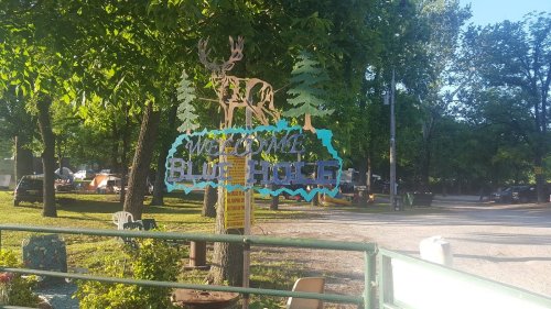 A colorful sign reading "Welcome to Blue Ridge" with a deer and trees, set in a green park area.