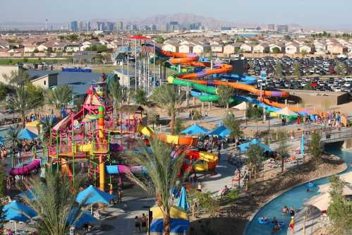 A vibrant water park with colorful slides, pools, and families enjoying the attractions against a city skyline backdrop.