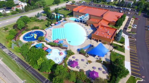 Aerial view of a large outdoor pool complex with slides, play areas, and surrounding greenery.