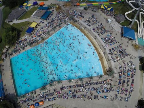 Aerial view of a crowded water park with a large pool and numerous sunbathers around it.