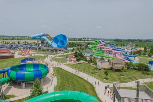 Aerial view of a water park featuring colorful slides, pools, and visitors enjoying the attractions on a sunny day.
