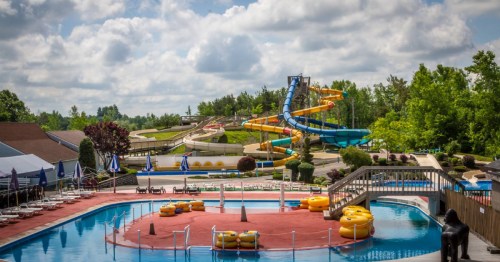 A vibrant water park featuring colorful slides, a pool, and lounge chairs under a partly cloudy sky.