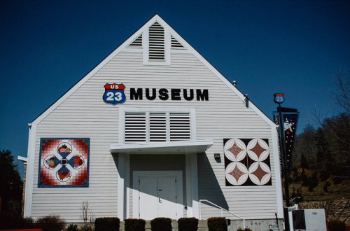 Exterior of the US 23 Museum, featuring a white building with colorful murals and a blue sky in the background.