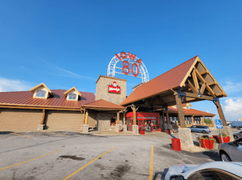 Exterior of Iowa 80 truck stop featuring a Wendy's, with a blue sky and parking lot in view.