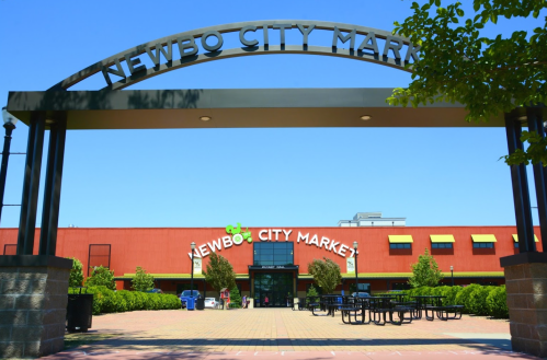 Entrance to Newbo City Market with a clear blue sky and outdoor seating visible in front.