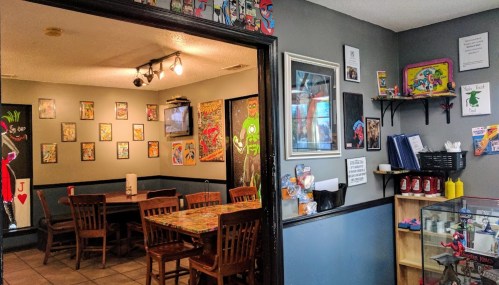 A colorful restaurant interior with comic art on the walls, wooden tables, and a cozy dining area.