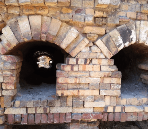 Close-up of brick arches in an old structure, revealing empty openings and weathered bricks.