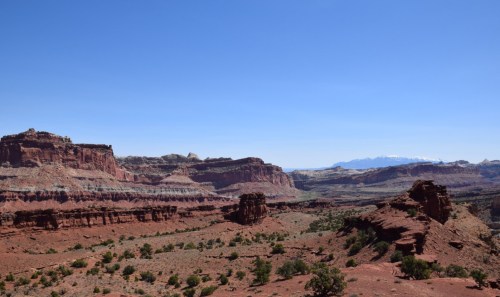 A vast desert landscape with rocky formations and distant mountains under a clear blue sky.
