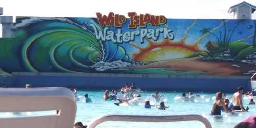 A vibrant mural of a sunset and waves at Wild Island Waterpark, with people floating in the pool below.