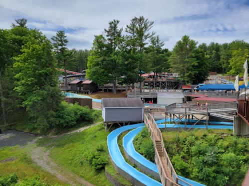 A view of a water park featuring blue slides, green trees, and various attractions in the background.