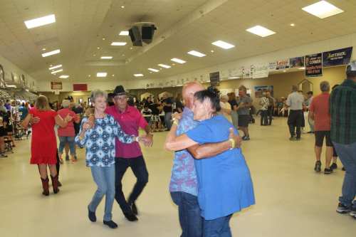 A lively dance event with people enjoying themselves on the dance floor, smiling and interacting in a spacious hall.