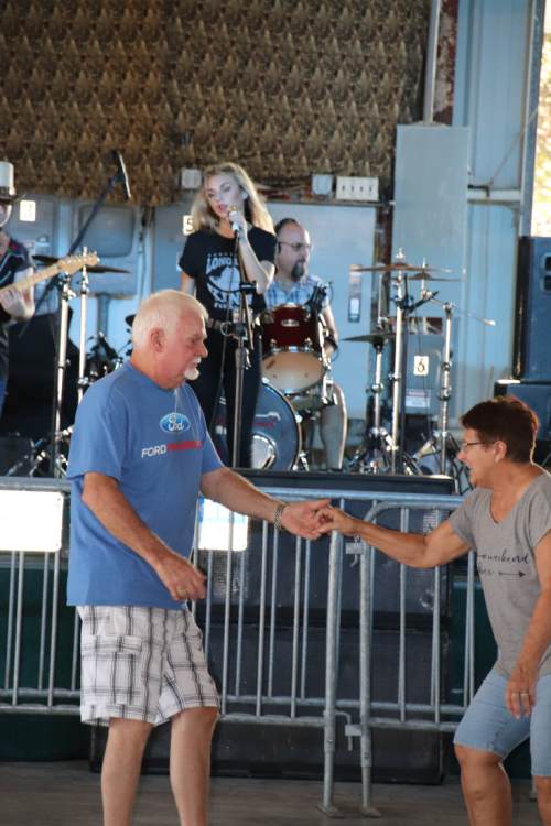 A couple dances joyfully in front of a live band performing on stage.