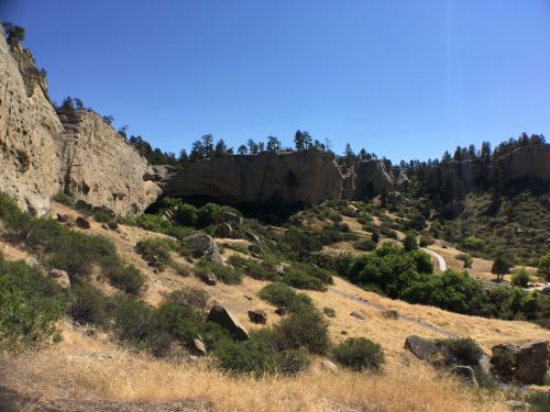 A scenic view of rocky cliffs and green vegetation under a clear blue sky.