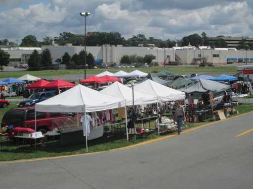 Aerial view of a bustling outdoor market with white tents, tables of goods, and shoppers browsing.