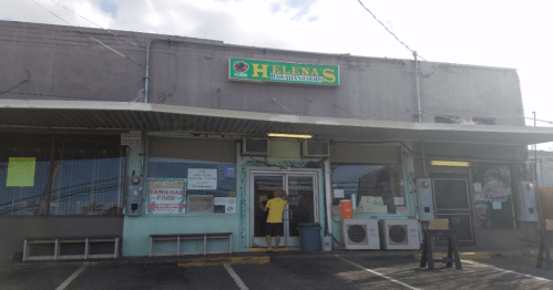 Exterior of Helena's Hawaiian Food restaurant, featuring a sign and a person in a yellow shirt at the entrance.