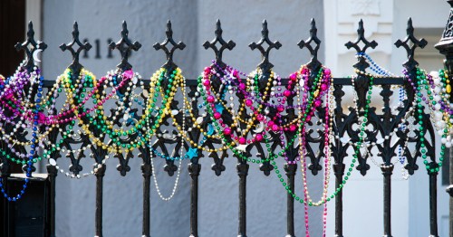 Several Mardi Gras beads on a fence in New Orleans.