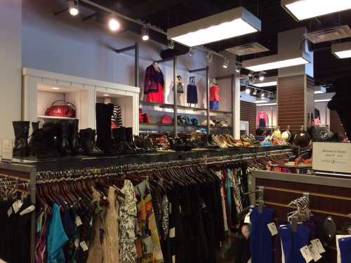 A retail store display featuring clothing, shoes, and accessories on racks and shelves.