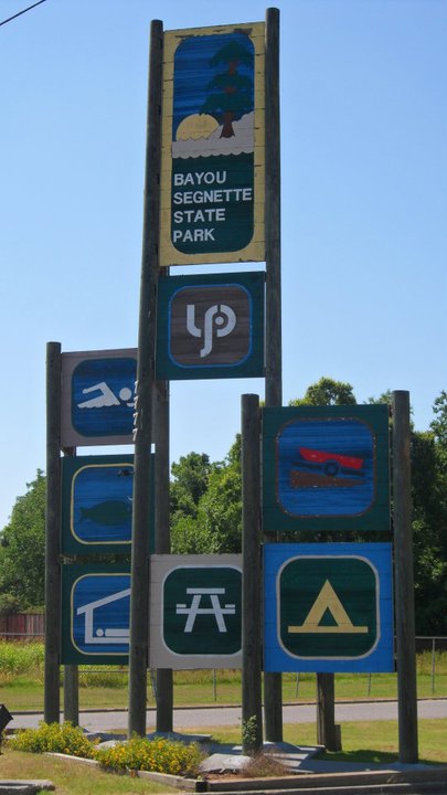 Sign for Bayou Segnette State Park featuring icons for swimming, camping, and other recreational activities.