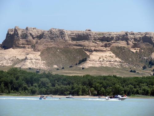 A scenic view of a river with boats, framed by a rocky cliff and lush greenery in the background.