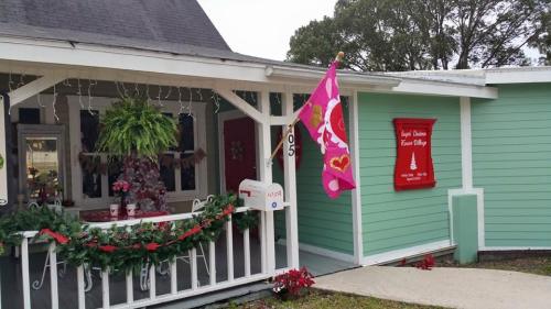 A charming house with a porch decorated for the holidays, featuring a pink flag and festive greenery.