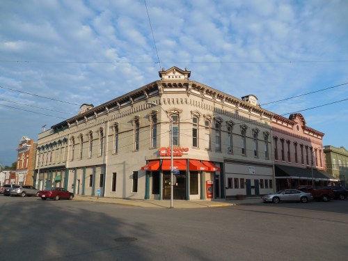 Historic building at a street corner, featuring ornate architecture and colorful facades under a cloudy sky.
