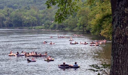 People floating on inner tubes in a river surrounded by lush greenery and hills.