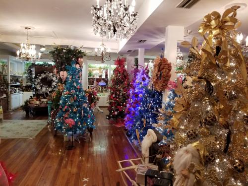 A festive room filled with colorful Christmas trees, twinkling lights, and holiday decorations.