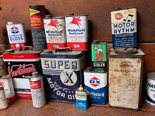 A collection of vintage oil cans and containers with various brands and designs displayed on a wooden shelf.