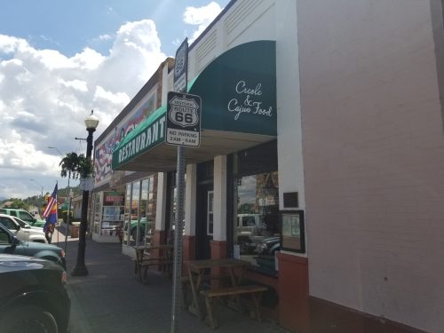 Exterior view of a restaurant featuring a sign for Creole & Cajun food, with a Route 66 marker nearby.