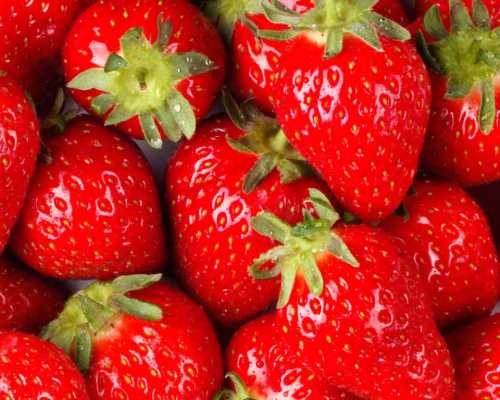 A close-up of fresh, ripe strawberries with vibrant red color and green leafy tops.