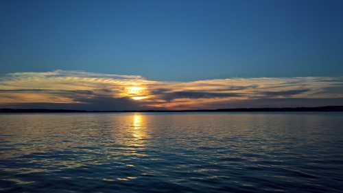 A serene sunset over a calm lake, with colorful clouds reflecting on the water's surface.