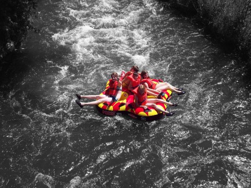 A group of people in red life jackets enjoying a colorful inflatable raft on a rushing river.