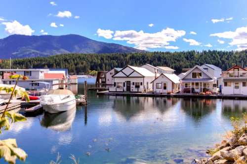 A serene marina with houseboats and a mountain backdrop under a clear blue sky.