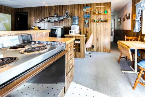 A retro kitchen with wood paneling, a stove, a water cooler, and a small dining area with a table and chairs.