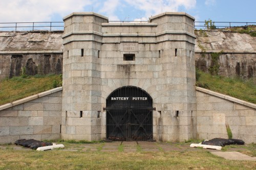 Stone entrance of Battery Potter, featuring a large archway and grassy surroundings under a cloudy sky.