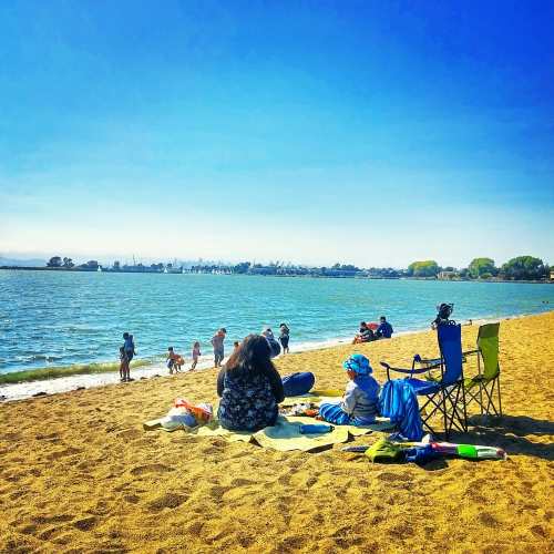 A sandy beach scene with people enjoying the sun, water, and activities along the shore.