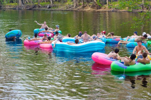 A group of people relaxes on colorful inflatable rafts in a river, enjoying a sunny day outdoors.