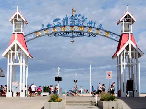 Colorful entrance archway to the Ocean City Boardwalk, with people walking and a cloudy sky in the background.