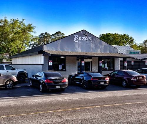 Exterior of Bozo's restaurant with parked cars in front and a clear blue sky above.